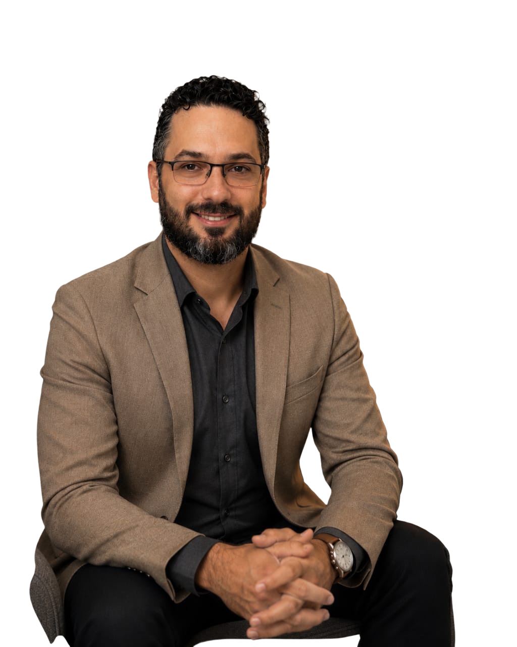 Ricardo Avelar sorrindo, de blazer bege, sentado em uma poltrona